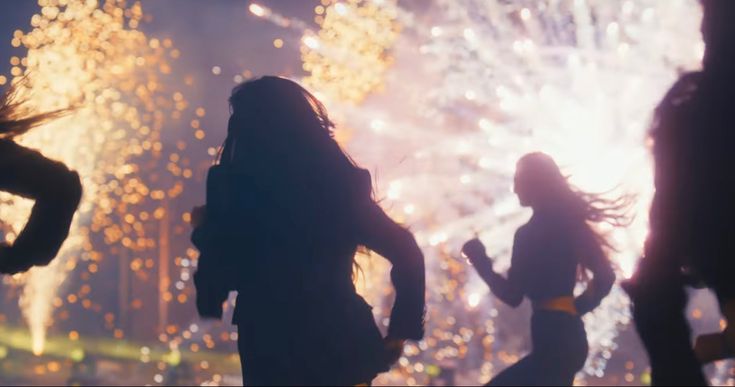 three women are standing in front of fireworks and watching them run down the street at night