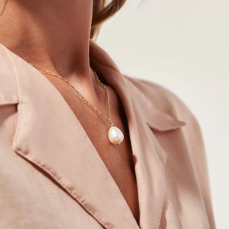 a woman wearing a pink shirt and pearl necklace