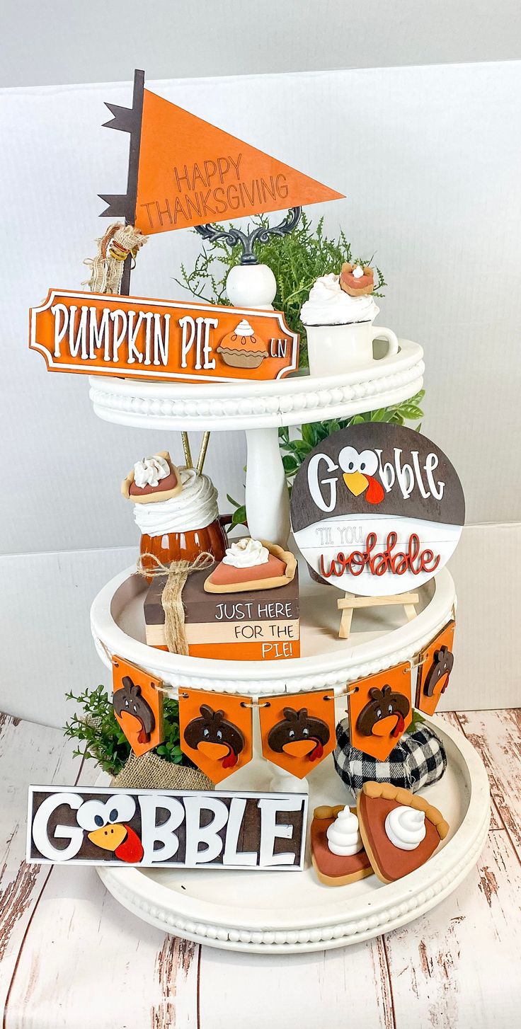 there is a three tiered cake stand with pumpkin pies and other decorations on it