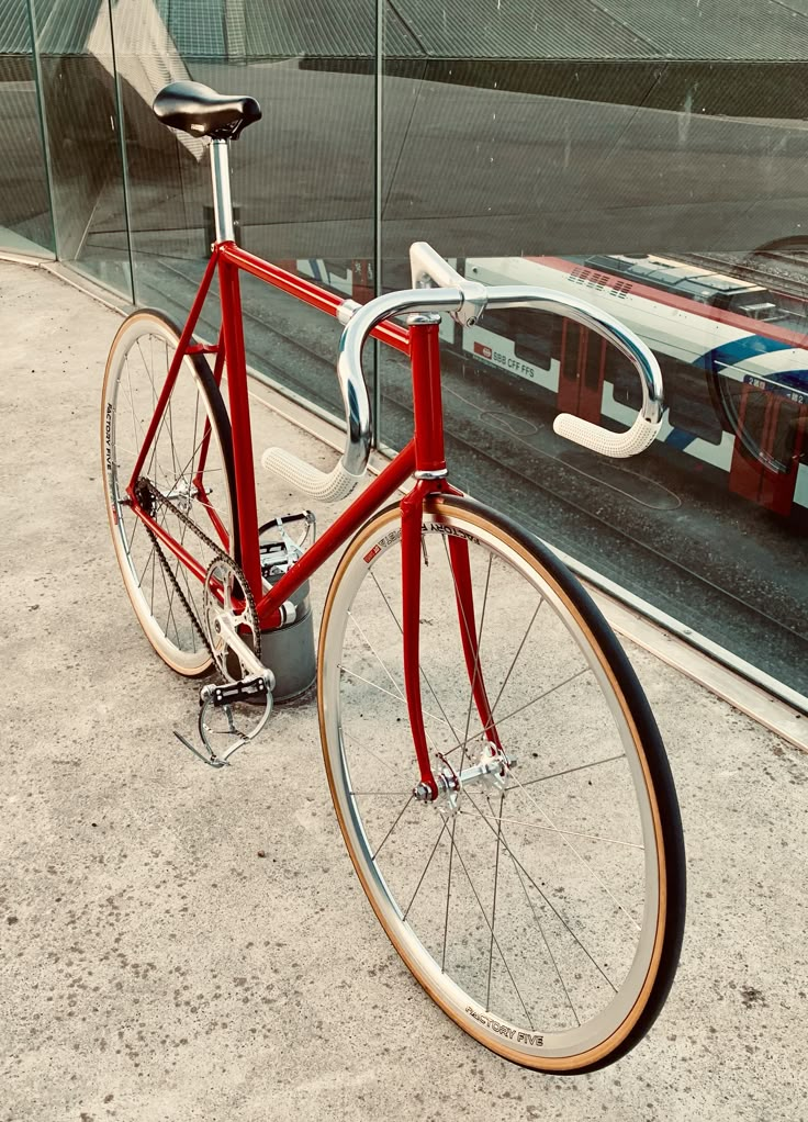 a red bicycle parked next to a train track