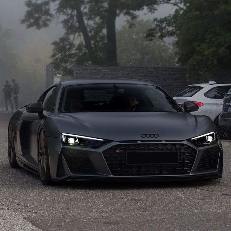 an audi sports car driving down the road in front of other cars on a foggy day