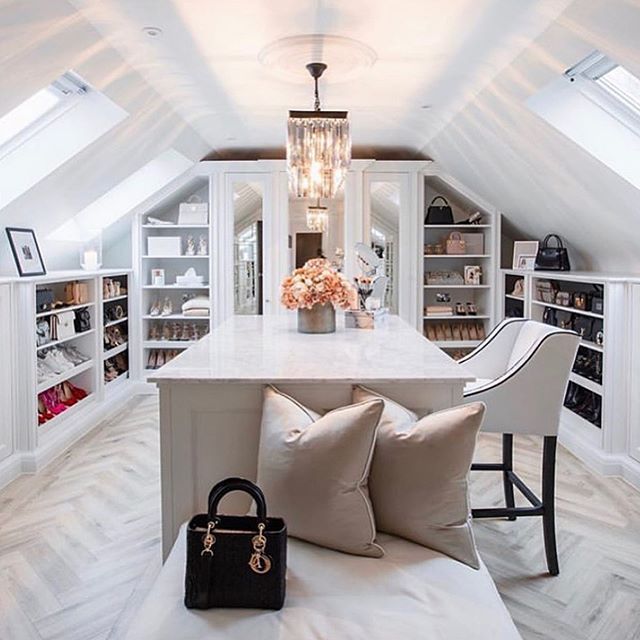 a room with white walls and lots of shelves filled with purses, handbags and other items