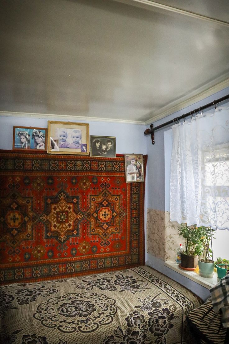 a room with a bed, rugs and pictures hanging on the wall above it