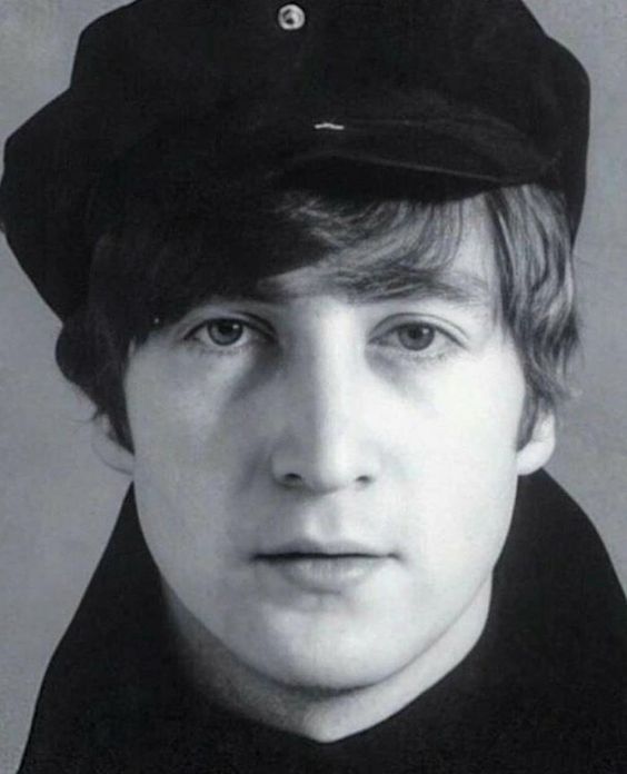 a black and white photo of a young man wearing a hat with buttons on it