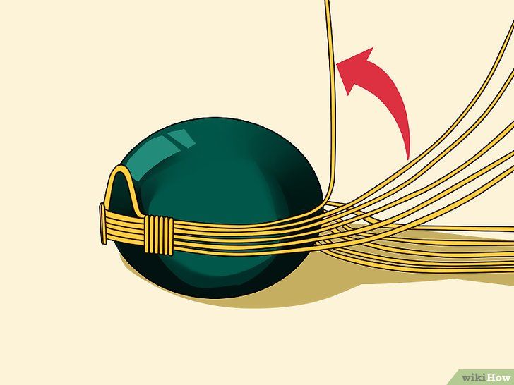 a green ball with gold wire wrapped around it and an arrow pointing to the side