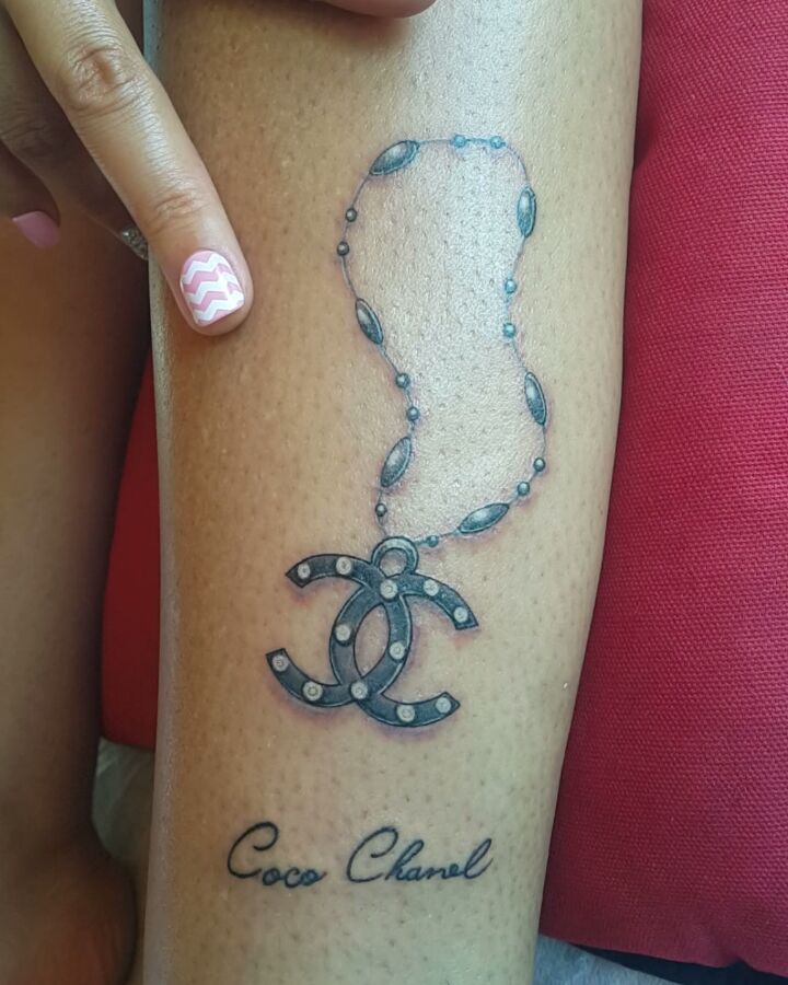 a woman's arm with a tattoo that says coco chan on it and a chain around the wrist