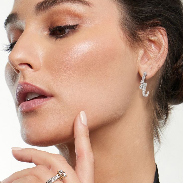 a woman with her hand on her chin, wearing two rings and a black shirt