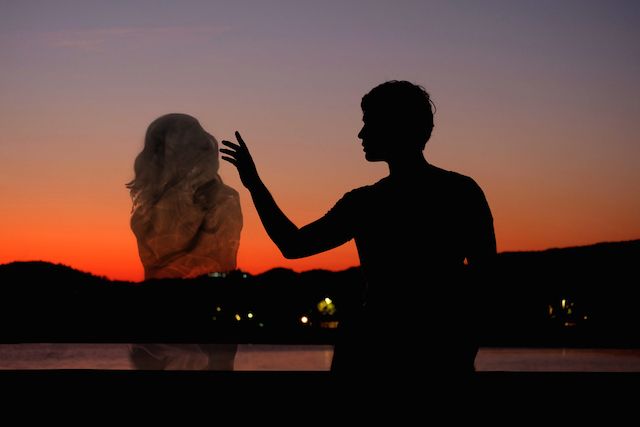 a man and woman standing next to each other at sunset