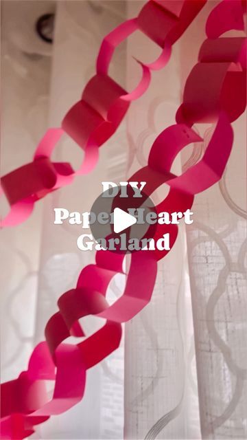 pink streamers hanging from the ceiling with text overlaying it that reads diy paper heart garland