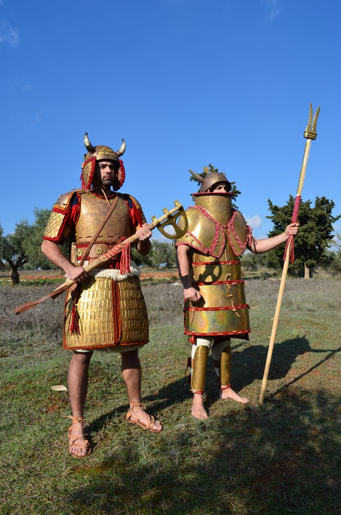 two men dressed in roman armor and holding spears