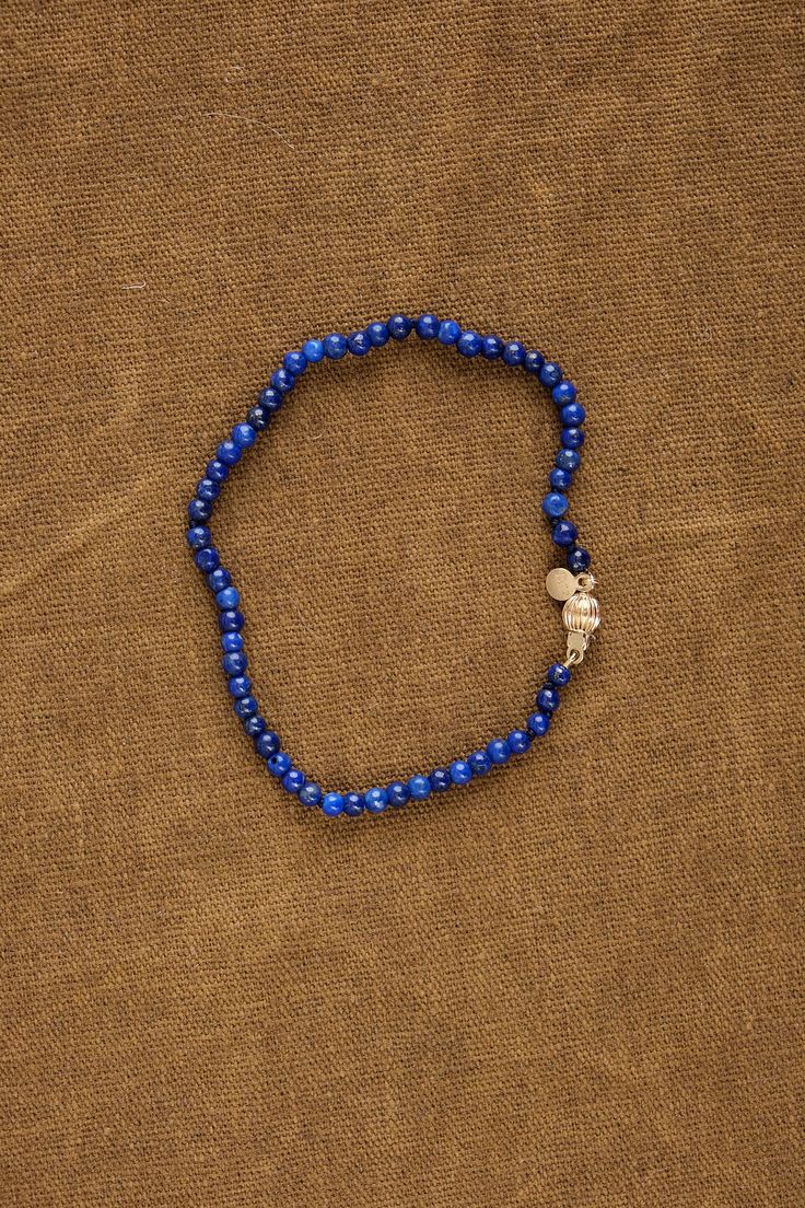 a blue beaded bracelet with an elephant charm on it's end, sitting on a brown cloth