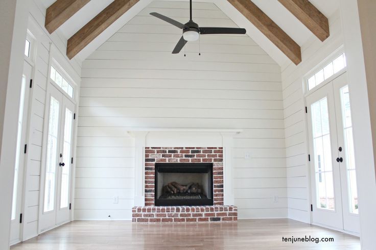 an empty living room with white walls and wood beams on the ceiling is shown in this image