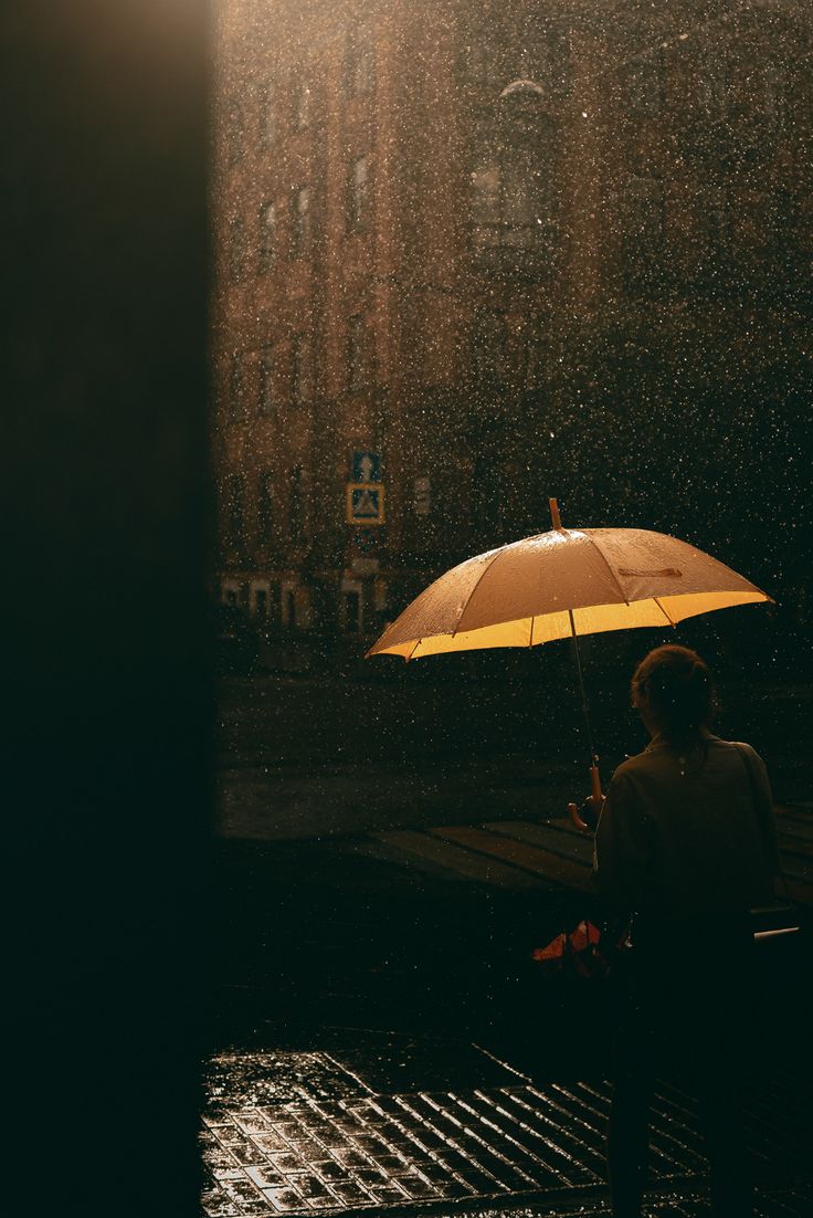 a person sitting under an umbrella in the rain