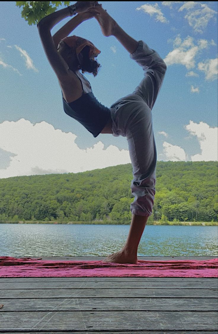 a woman doing yoga on a dock by the water