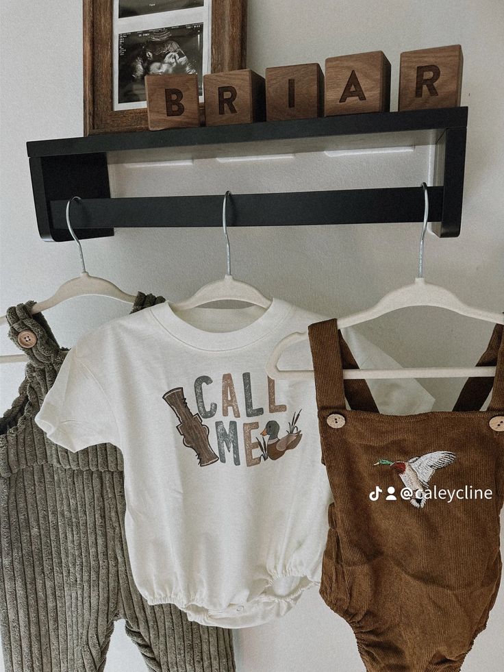 two baby onesuits are hanging on a clothes rack with the name call me