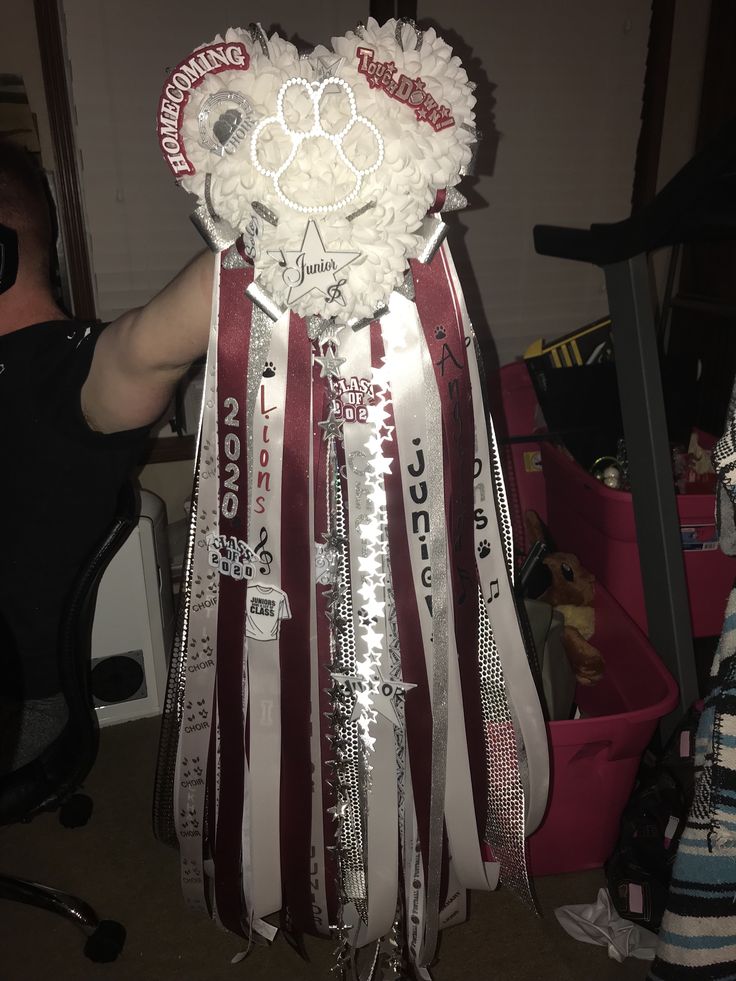 a man is holding up a bouquet made out of ribbon and paper mache strips