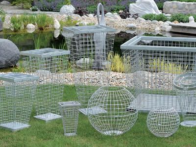 several metal cages sitting in the grass near water