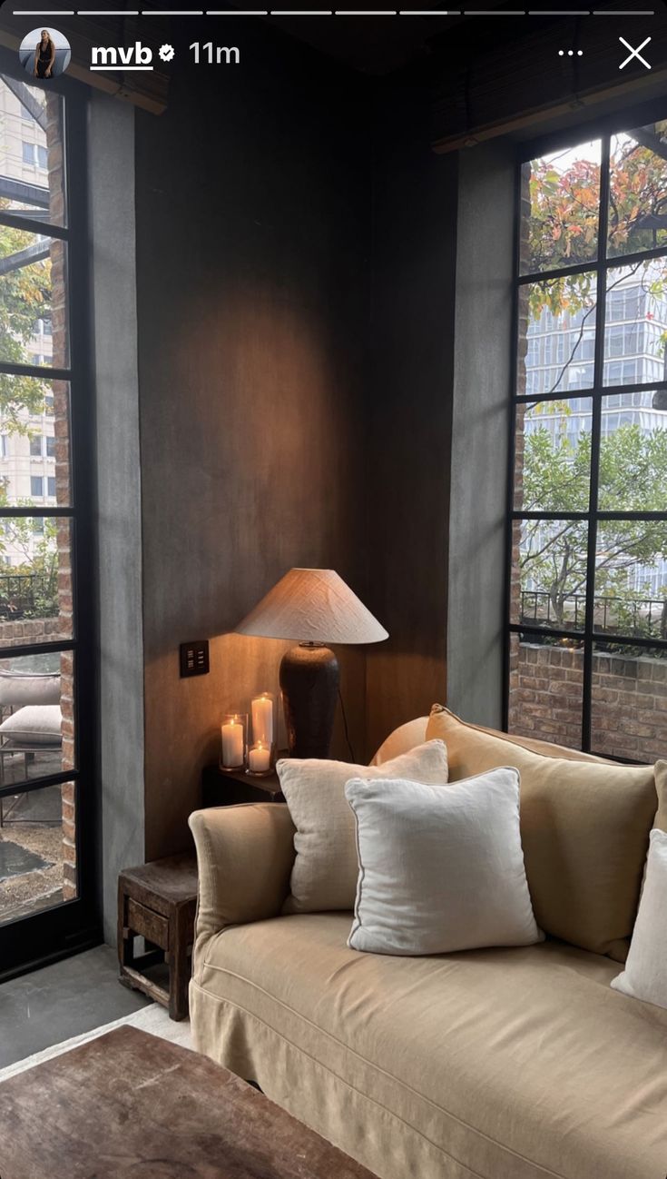 a living room filled with lots of furniture next to large windows and a lamp on top of a table