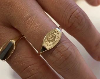 a close up of a person's hand wearing a gold ring with a coin on it