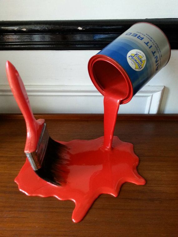 a red paint can being poured onto a wooden floor