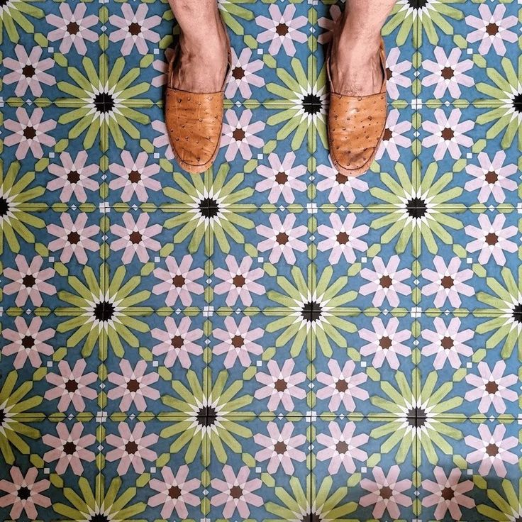 a person standing on a tiled floor with their feet propped up in the air and wearing brown shoes