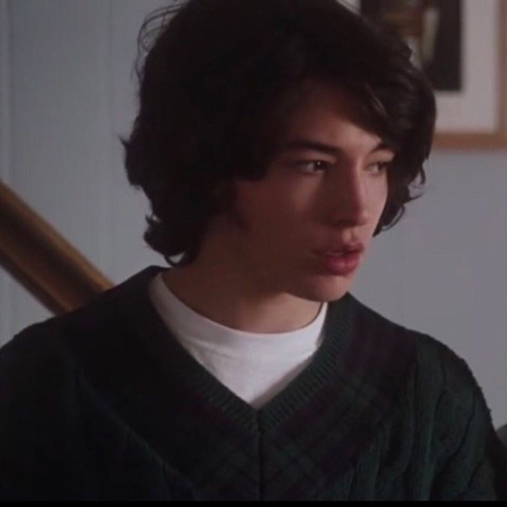 the young man is wearing a sweater and looking off into the distance with his eyes wide open