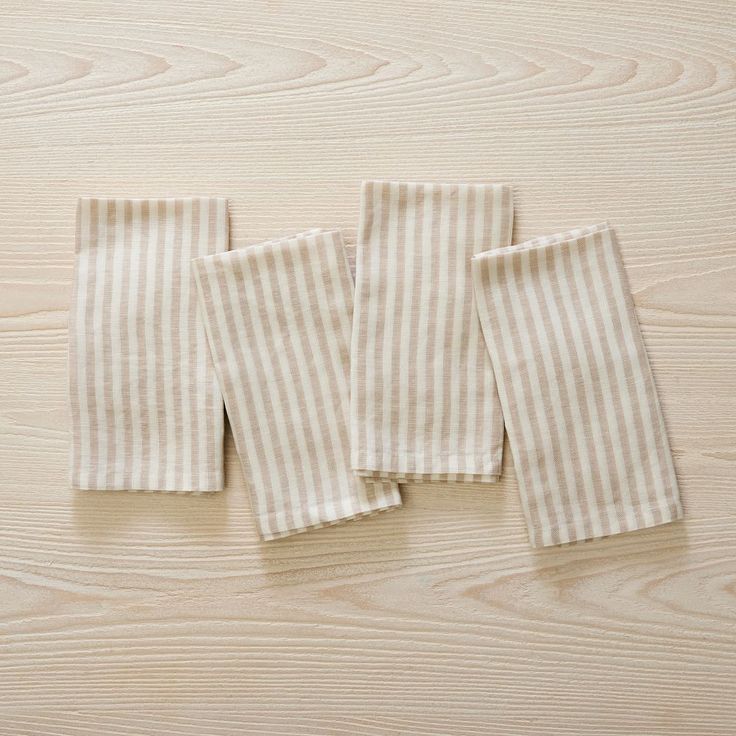 three white and beige striped towels laying on top of a wooden table