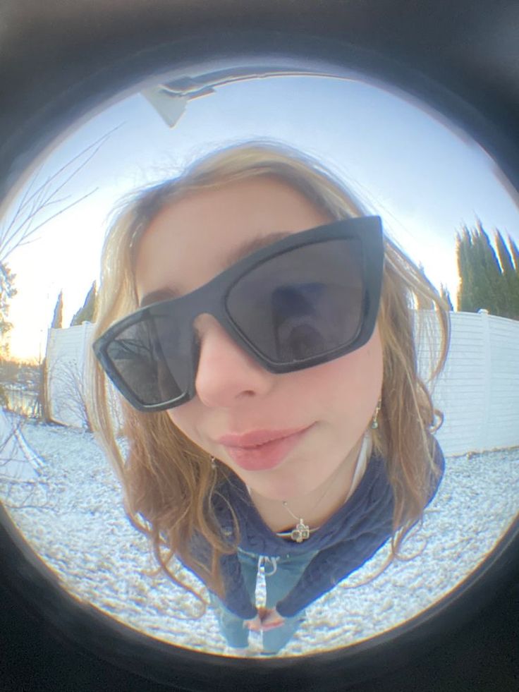 a woman wearing sunglasses is taking a selfie in the reflection of another person's eye