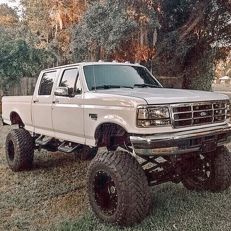 a white pickup truck parked on top of a lush green field