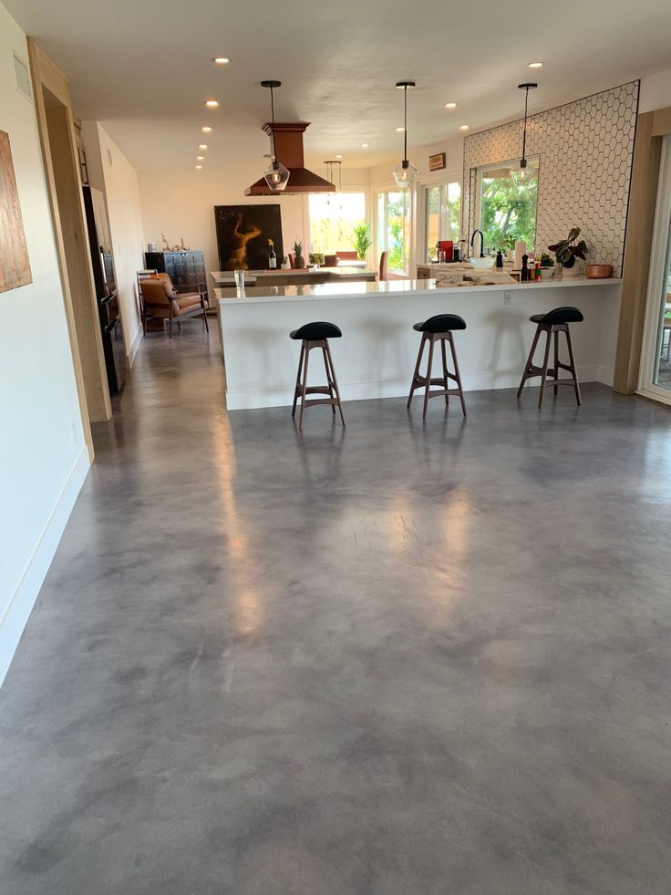 three stools are sitting in the middle of a large open floor plan kitchen and living room