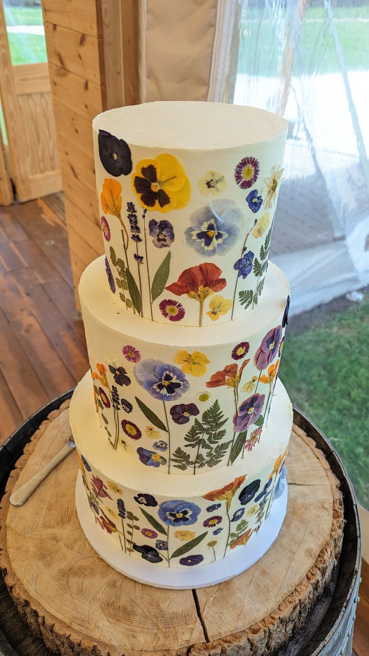 a multi layer cake sitting on top of a tree stump