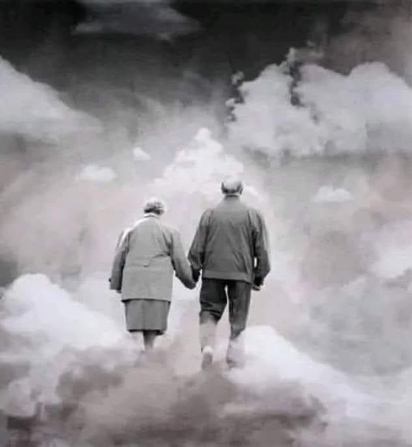 two people are walking in the clouds holding each other's hands and looking into the distance