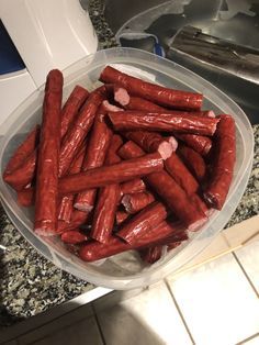 a plastic container filled with hot dogs on top of a counter