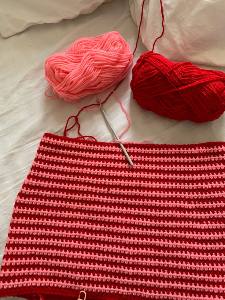 two skeins of yarn are laying on a bed next to a crochet bag