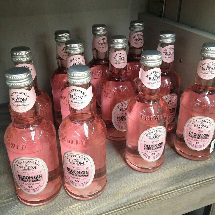 many bottles of pink liquid are lined up on a shelf