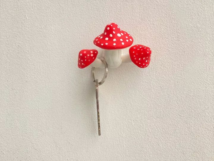 a red and white mushroom shaped light on the side of a wall with three holes in it