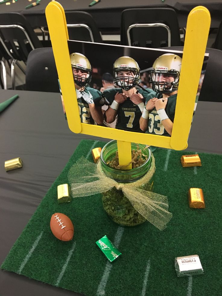 a football themed centerpiece with candy and candies on a table in a stadium