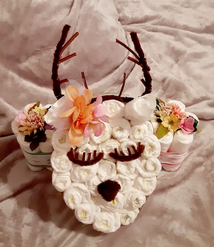 a cake shaped like a deer with flowers on it's head and two cupcakes to the side