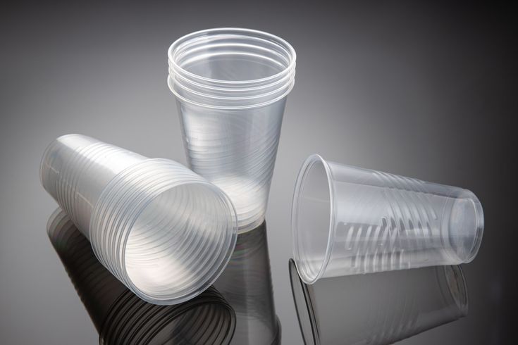 three plastic cups sitting next to each other on top of a reflective surface with reflections