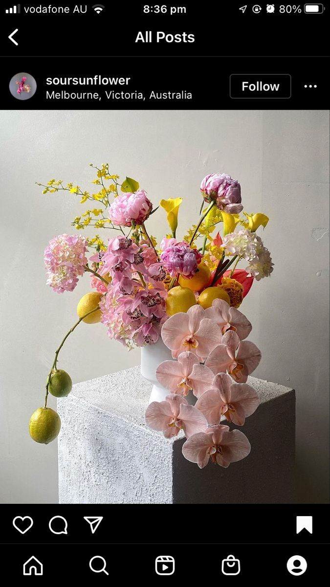 a vase filled with lots of flowers sitting on top of a white table next to a wall