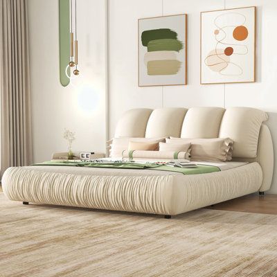 a large white bed sitting on top of a wooden floor