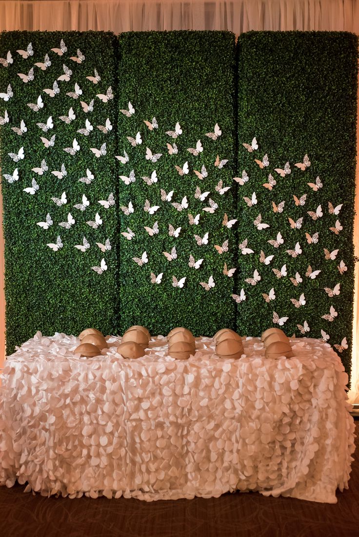 a table topped with lots of eggs sitting next to a wall covered in green grass