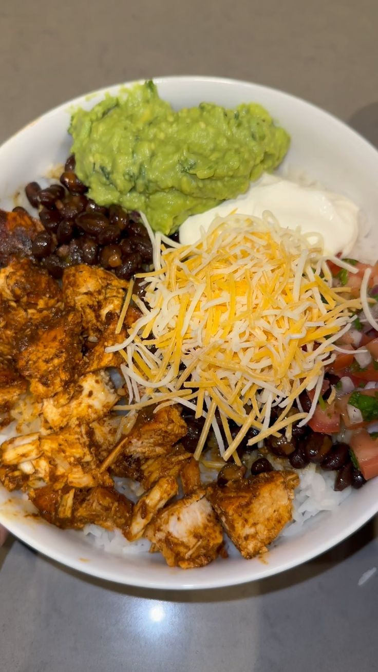 a white plate topped with meat, beans and guacamole