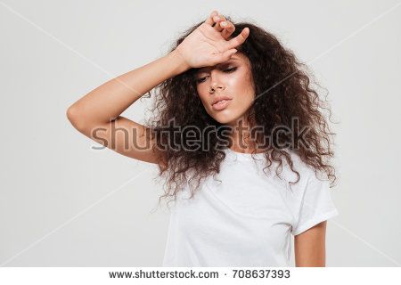 a young woman with curly hair covering her eyes and holding her hands to her head