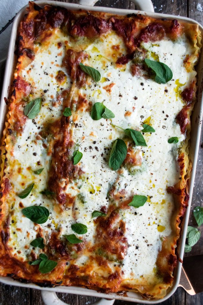 a casserole dish with cheese and basil on top, ready to be eaten