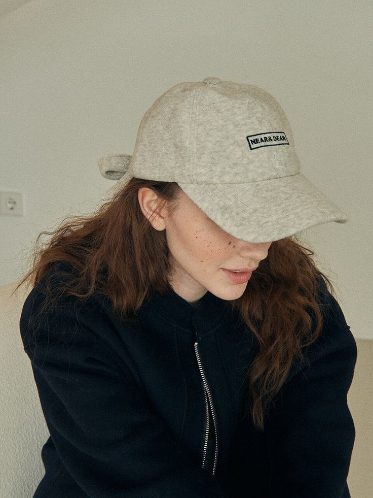 a woman sitting on a couch wearing a hat and looking down at her cell phone