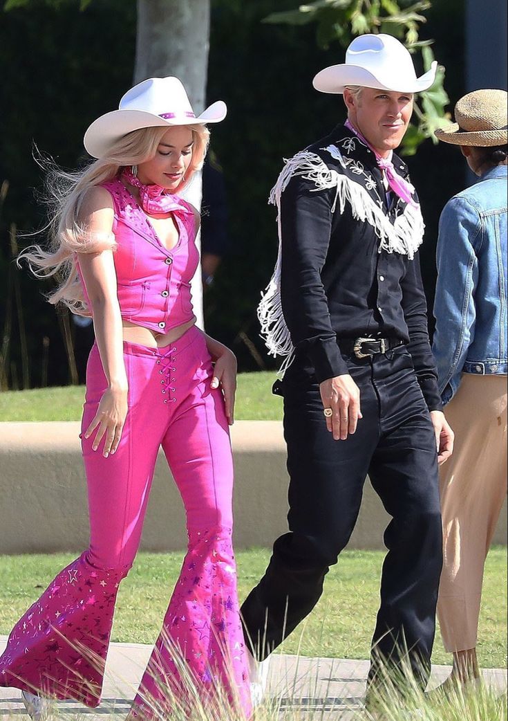 a man and woman in cowboy hats walking down the street