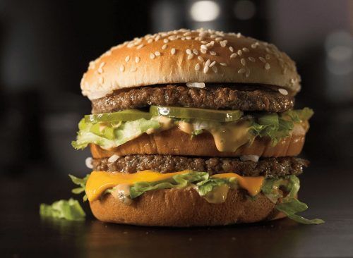 a hamburger with cheese and lettuce on it sitting on top of a table