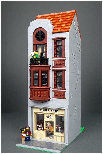 a building made out of legos is shown in front of a gray background with an orange roof