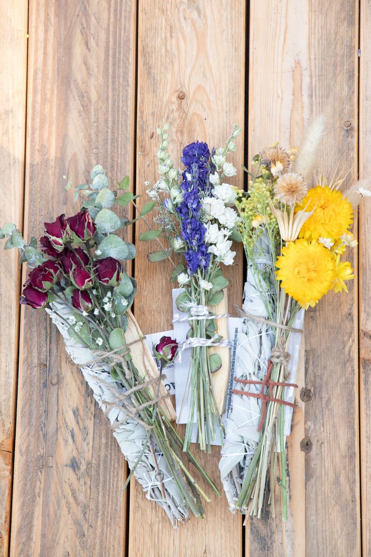 flowers laid out on top of each other in front of a wooden fence with paper wrapped around them